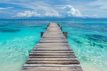 Naklejka premium Wooden pier leading to the ocean with a white sand beach and turquoise water, tropical island background, copy space for text in a wide format in the style of tropical island background.