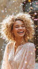 A woman with curly hair is joyfully smiling as confetti falls around her, capturing a moment of celebration and happiness