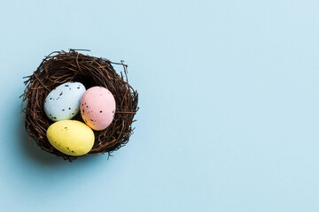 Colorful easter eggs in nest on table background with copy space top view