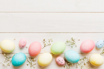 Happy Easter composition. Easter eggs on colored table with gypsophila. Natural dyed colorful eggs background top view with copy space