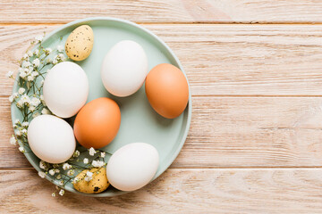 Happy Easter composition. Easter eggs in basket on colored table with gypsophila. Natural dyed colorful eggs background top view with copy space