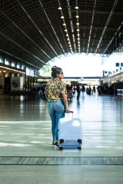 Woman Walking Through Airport with Suitcase