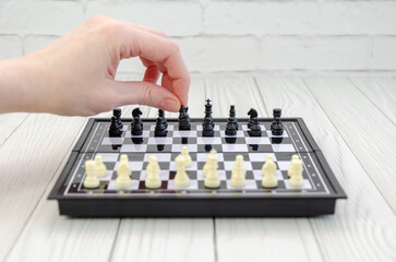 Close-up of woman's hand arranging chess pieces on chessboard before the start of tournament