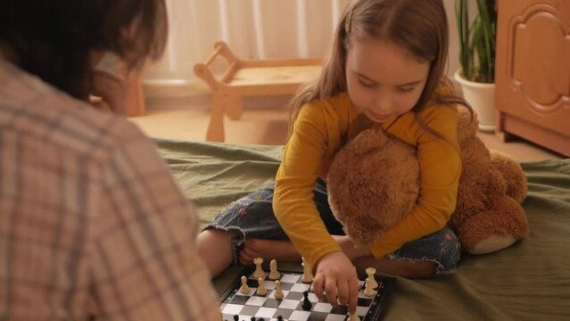 Playful father-daughter duo engage in bedroom chess match