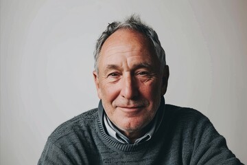 Portrait of an elderly man in a gray sweater on a gray background