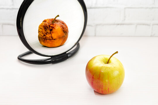 fresh apple appears wrinkled and rotten in reflection of mirror. Concept of psychology, self esteem