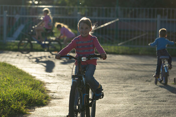 girl in a pink jacket rides a bicycle, sports for children, cycling, summer walk, childhood,...