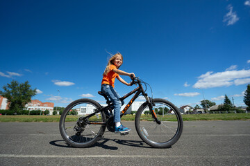 Fototapeta na wymiar girl in an orange sweater rides a bicycle