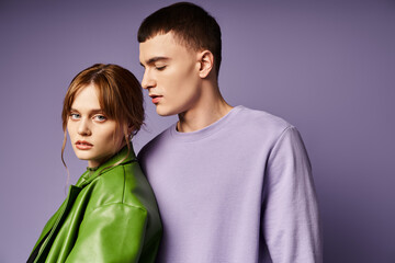 beautiful girlfriend in green attire looking at camera near her boyfriend in purple sweatshirt