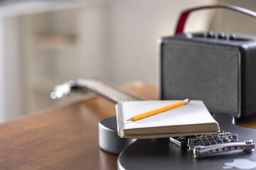 Black electric guitar, notebook and speaker close-up.