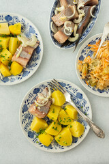 Delicious hearty fish dinners, boiled potatoes with pickled herring, sauerkraut with onions and olive oil, top view