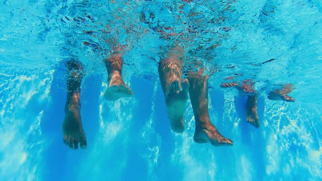 Underwater view of people legs dangling in clear pool water