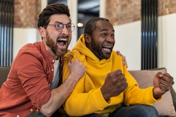 Two friends watching tv and looking excited and emotional