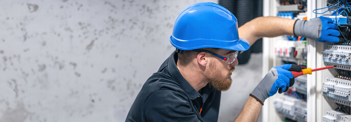 Electrician working in switchboard with electrical connection cable, copy space.