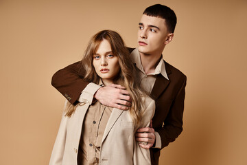 sophisticated man in debonair suit posing next to his beautiful girlfriend who looking at camera