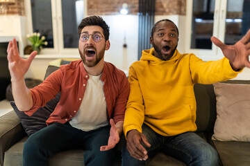 Two friends spending time together watching tv and looking excited
