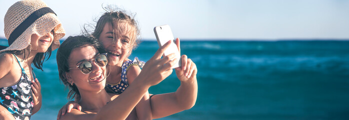 A mother with a child takes a selfie on a background of the sea and sea waves.