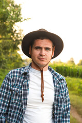 A young farmer standing proudly in a lush green soybean field, representing the dedication, hard work of agricultural professionals in cultivating essential crops. Vertical portrait of young farmer