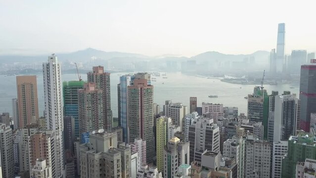 Aerial Panning Shot Of Modern Residential Buildings In City By Sea And Mountains Against Clear Sky - Hong Kong, China