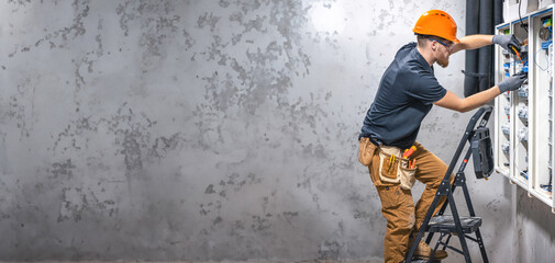 Electrician working in switchboard with electrical connection cable, copy space.