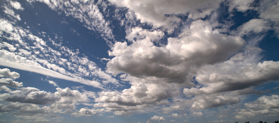 Sun shining through the puffy clouds. Sky view. Beautiful sunny sky. Background with clouds on blue...