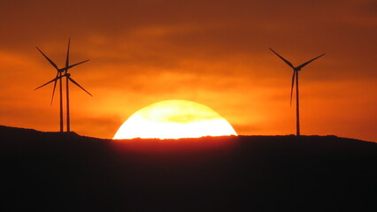 windmills between zoom sun sunset energy crisis renewable ecology