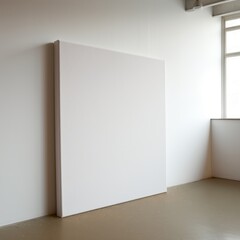 Large Blank Canvas Leaning Against a White Wall in a Sunlit Studio