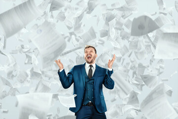 A businessman, an office worker in a suit stands under falling documents. Overwhelmed with work, overwork, fatigue, overtime.