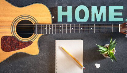 Acoustic guitar, notepad and decorative word Home, top view.