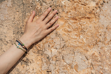 Woman hand with different bracelets on the old stone wall