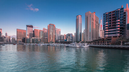 Dubai Marina towers and yachts reflected in water of canal in Dubai day to night timelapse