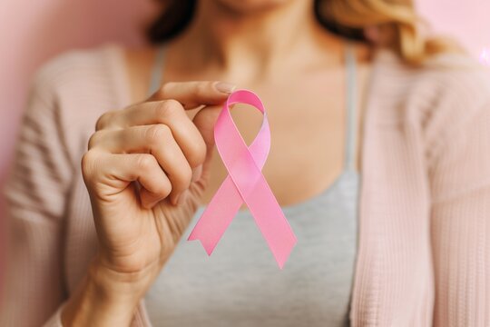 The woman showing love and support to women fighting against cancer with a pink ribbon in hand