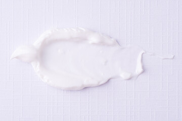 Texture of the white cream on a white background. White cream smudge swatch textured. Cosmetic smear of creamy texture.
