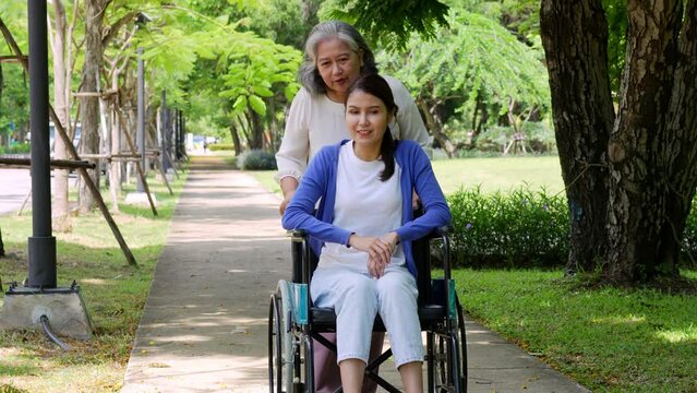 Happy young woman in wheelchair in park outdoors with mother, gorgeous positive girl in wheelchair rejoicing at new day, positive feeling and emotion. cheerfulness, physical recovery concept