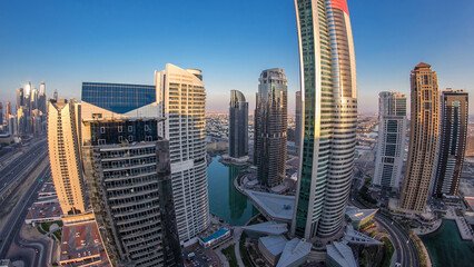 Buildings of Jumeirah Lakes Towers after sunset with traffic on the road day to night timelapse.