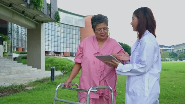 Asian careful caregiver or doctor taking care of the elderly Asian patient in hospital park. Concept of happy retirement with care from caregiver and Savings and senior health insurance. elderly care