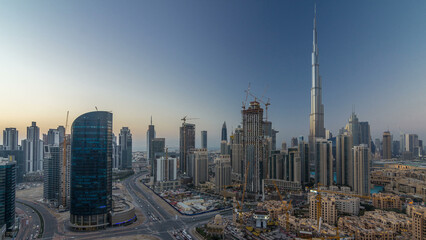 Naklejka na ściany i meble Dubai Downtown day to night timelapse. Aerial view over big futuristic city by night.