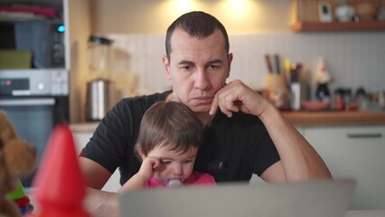 father working from home a remotely with baby daughter in his arms. pandemic fun remote work business concept. father tries to work at home in kitchen, baby children interfere sitting on their hands - 767105156