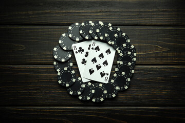Playing cards in the game of poker with black chips from winning on a vintage table in a clubhouse....