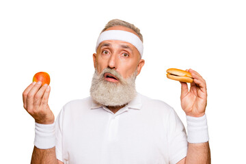 Athlete cool uncertain unsure ponder fit picky grandpa holds forbidden cheeseburger and fruit,...