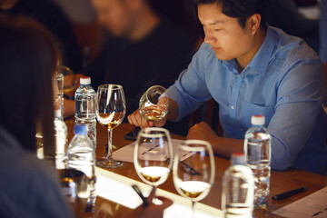 Asian Sommelier Tasting Wine at Table During Training