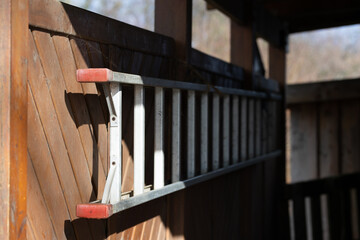 Eine Aluleiter seitlich aufgehängt in einem Carport aus Holz und Sicherschutzelementen nah am Wald...