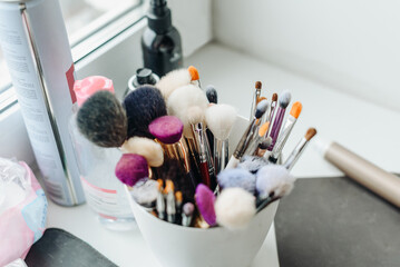 different make-up artist's brushes in a white glass