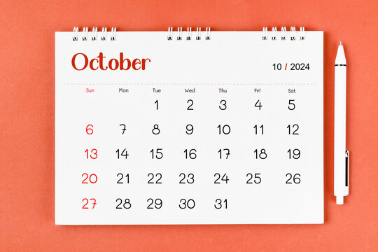 The October 2024 Monthly desk calendar for 2024 year and pen on red background.