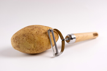 Raw potatoes and a knife for peeling on a white background.