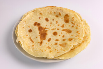 Freshly baked pancakes on a plate on a white background.
