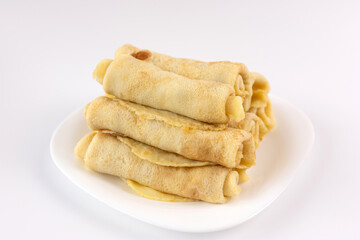 Freshly baked wrapped pancakes with filling on a plate on a white background.