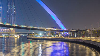 Futuristic Pedestrian Bridge over the Dubai Water Canal Illuminated at Night timelapse, UAE.