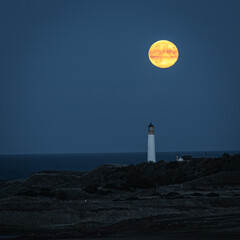 lighthouse at night with full harvest moon