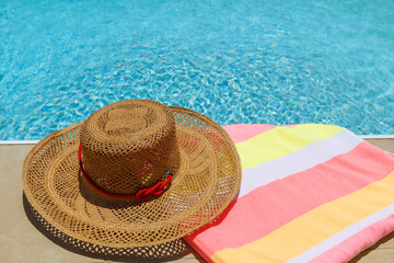Straw beach hat and towel on the edge of the pool
